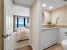 The second full bath includes a long vanity with abundant cabinet storage and a large wall mirror.