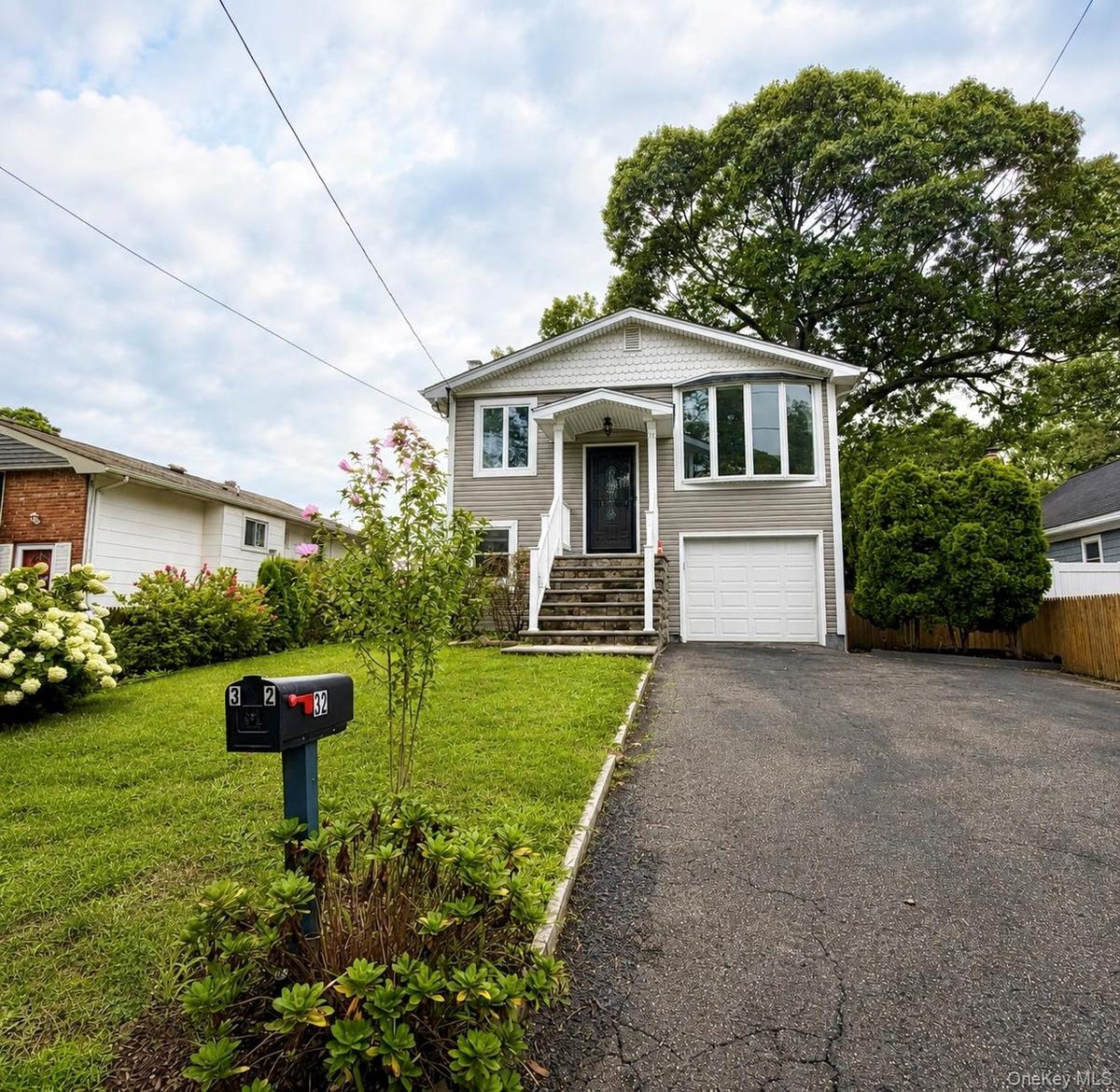Exterior featuring gray siding, a covered entry porch, a bay window, and an attached garage with a white door.