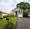 Exterior featuring gray siding, a covered entry porch, a bay window, and an attached garage with a white door.
