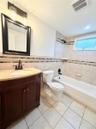 Bathroom featuring a single vanity with stone-finish countertop and  built-in bathtub.