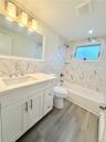 Bathroom featuring a single vanity with stone-finish countertop and  built-in bathtub.