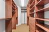 Custom walk-in closet features extensive built-in shelving, hanging space and drawer storage for a highly organized primary suite.