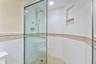 A glass-enclosed shower with tiled walls and built-in niche completes the bath.