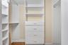 The walk-in closet provides extensive built-in shelving, hanging space and drawer storage.