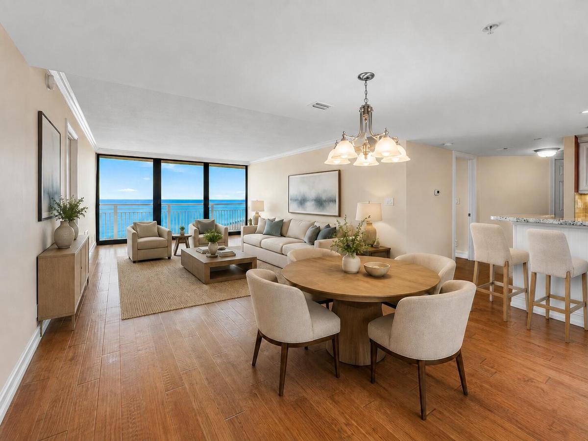 Virtually staged; residence is offered unfurnished. The open living and dining area is framed by direct Atlantic Ocean views, with the kitchen and bre