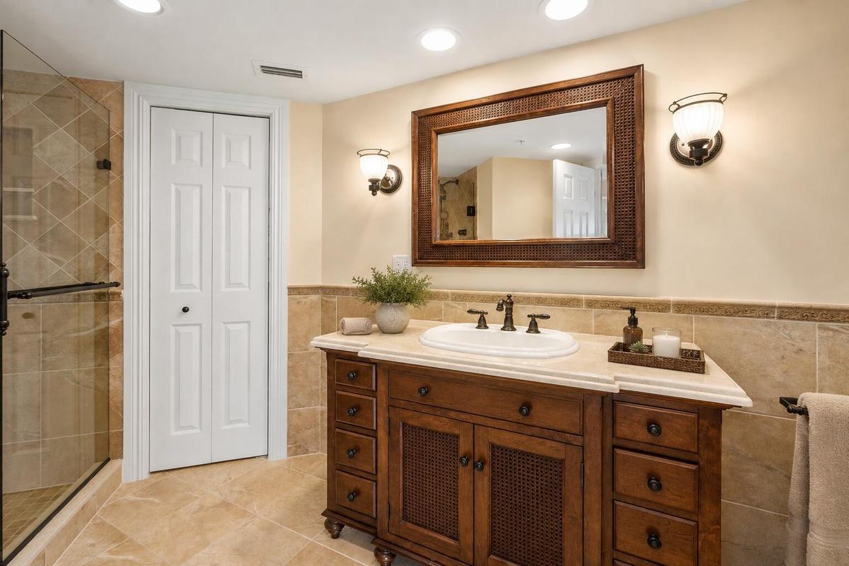 The primary bathroom combines a substantial vanity, tiled finishes and a glass-enclosed shower to create a comfortable, well-appointed en-suite retrea