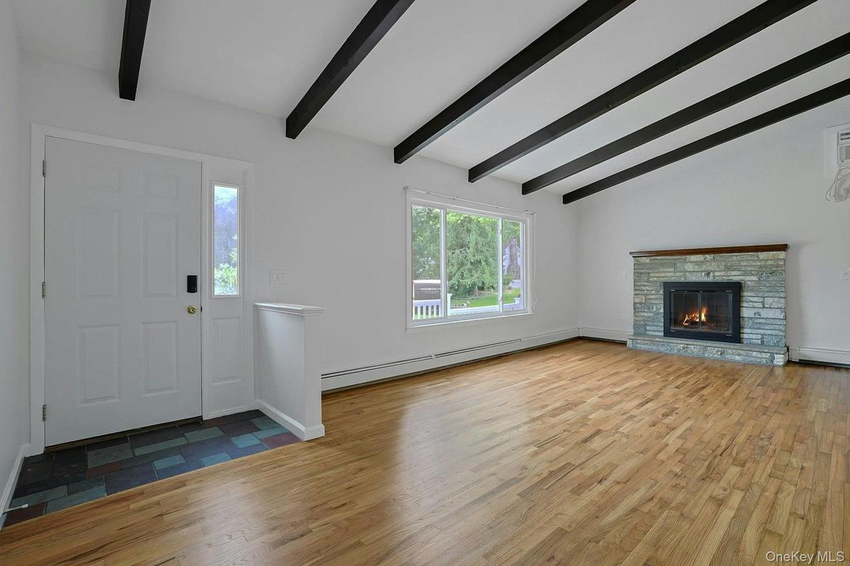 Living room with stunning hardwood floors, stone fireplace and beamed cathedral ceiling