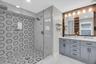 Spa-inspired primary bath features an oversized doorless walk-in shower with designer tile and dual shower heads.