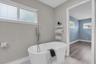 Freestanding clawfoot soaking tub and black iron fixtures complete the primary bath's modern coastal look.