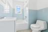 Bathroom featuring tile walls, vanity, shower / washtub combination, and wainscoting