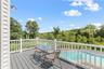 The primary bedroom’s private balcony overlooks the lush, landscaped backyard and sparkling in-ground pool, offering a serene retreat to savor your mo