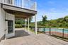 Outdoor patio with large format pavers, adjacent to a fenced in swimming pool with brick decking.