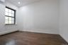 Wood-finish flooring, white walls, and a multi-pane window with dark trim