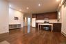 Rich wood-finish flooring throughout, recessed ceiling lighting, kitchen featuring wood cabinetry, stainless steel range and hood, and a white subway 