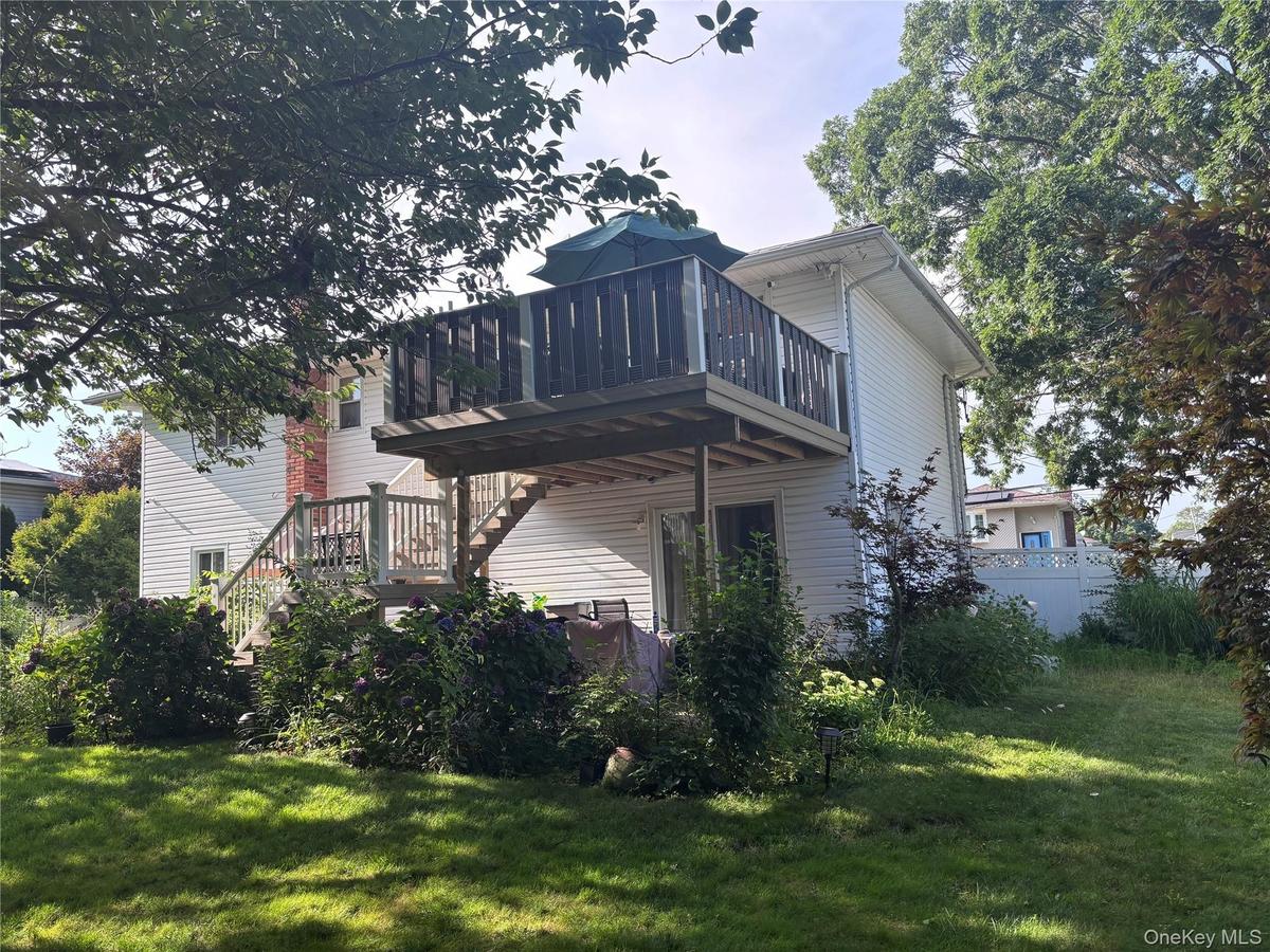 Two-story deck with wood railing, leading to a ground-level patio