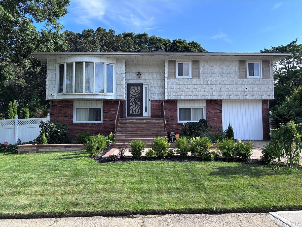 Split-level residence featuring brick and shake siding, a bay window, and exterior steps with railing