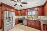 Kitchen with wood cabinetry, granite countertops, tile backsplash and stainless steel appliances.