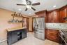 Kitchen with wood cabinetry, stainless steel appliances, tile flooring and additional storage space.