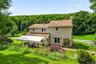 Rear exterior with patio, gardens, and wooded views.