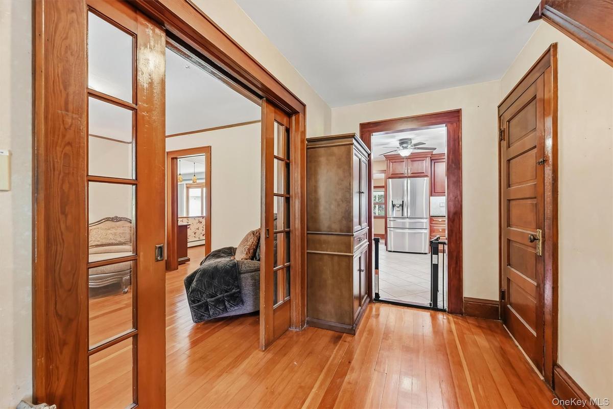 Front entry showcasing hardwood floors, wood trim, and glass-paneled pocket doors.