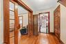 Front entry showcasing hardwood floors, wood trim, and glass-paneled pocket doors.