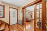 Front entry featuring hardwood floors, natural woodwork, and glass-paneled pocket doors leading into the living room.
