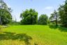 Expansive green lawn with mature trees and natural surroundings.