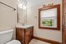 Full bathroom featuring a wood vanity, tiled flooring, and natural wood trim.