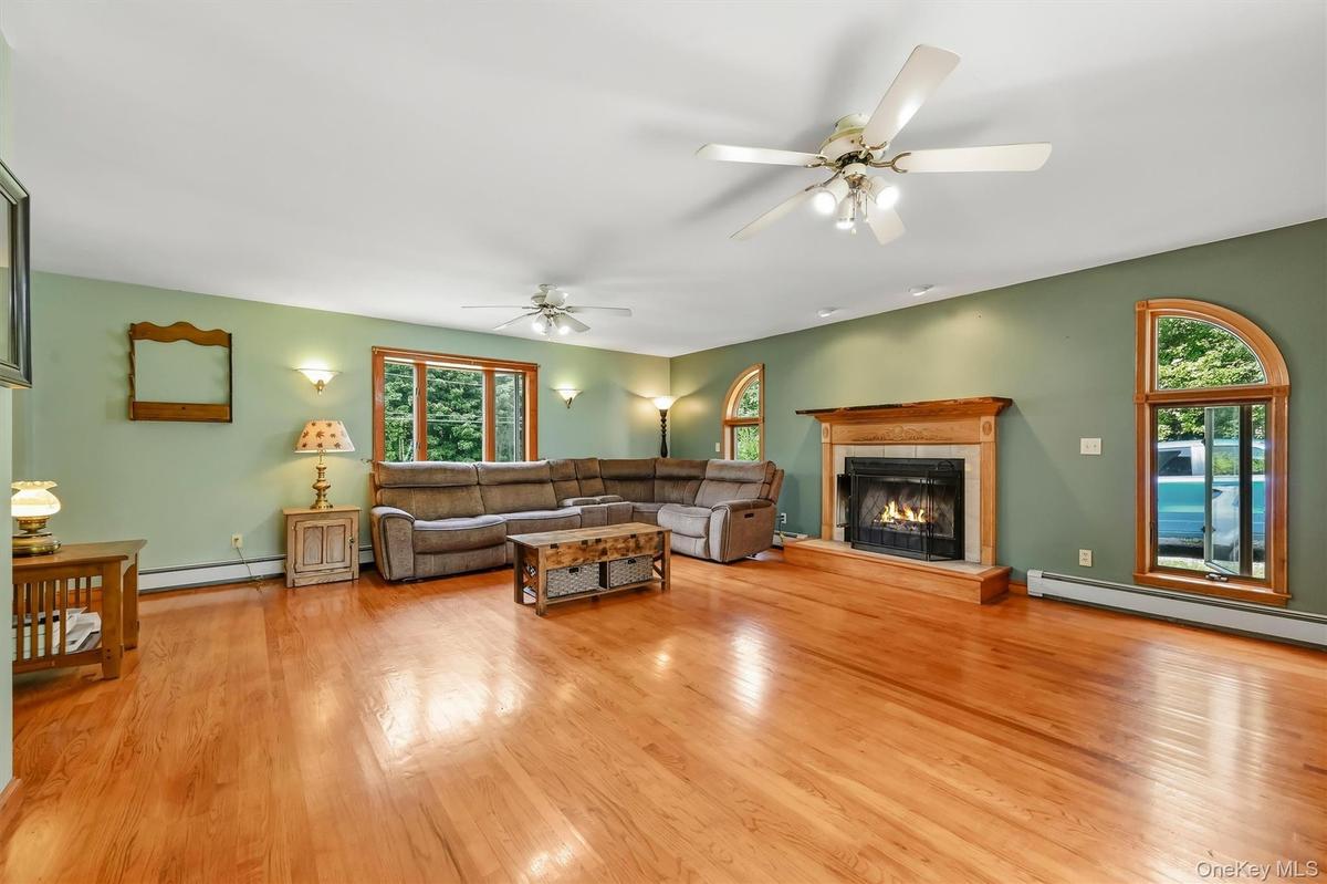 Spacious family room featuring hardwood floors, a fireplace, and distinctive arched windows.