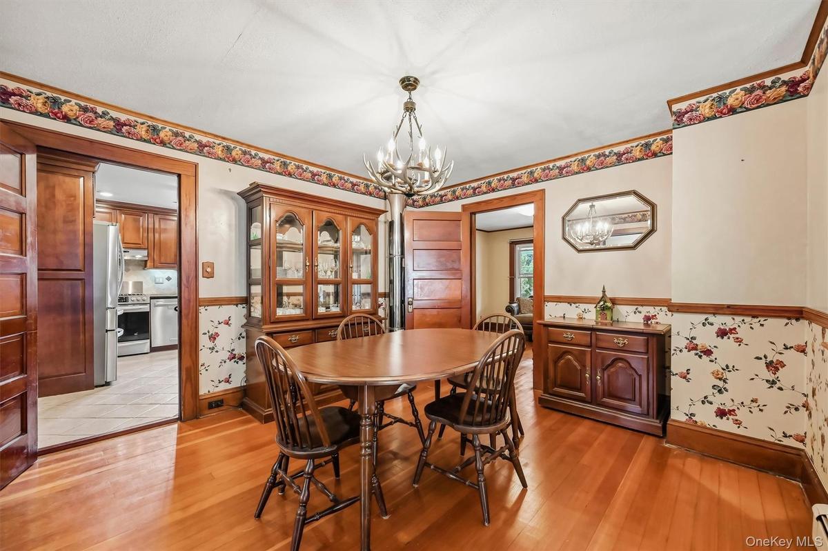 Dining room featuring hardwood floors, natural wood trim, and direct access to the kitchen.