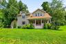 Front exterior featuring a covered porch, spacious lawn and detached garage.