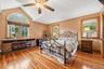 Primary bedroom with hardwood floors, vaulted ceiling and a large arched window.