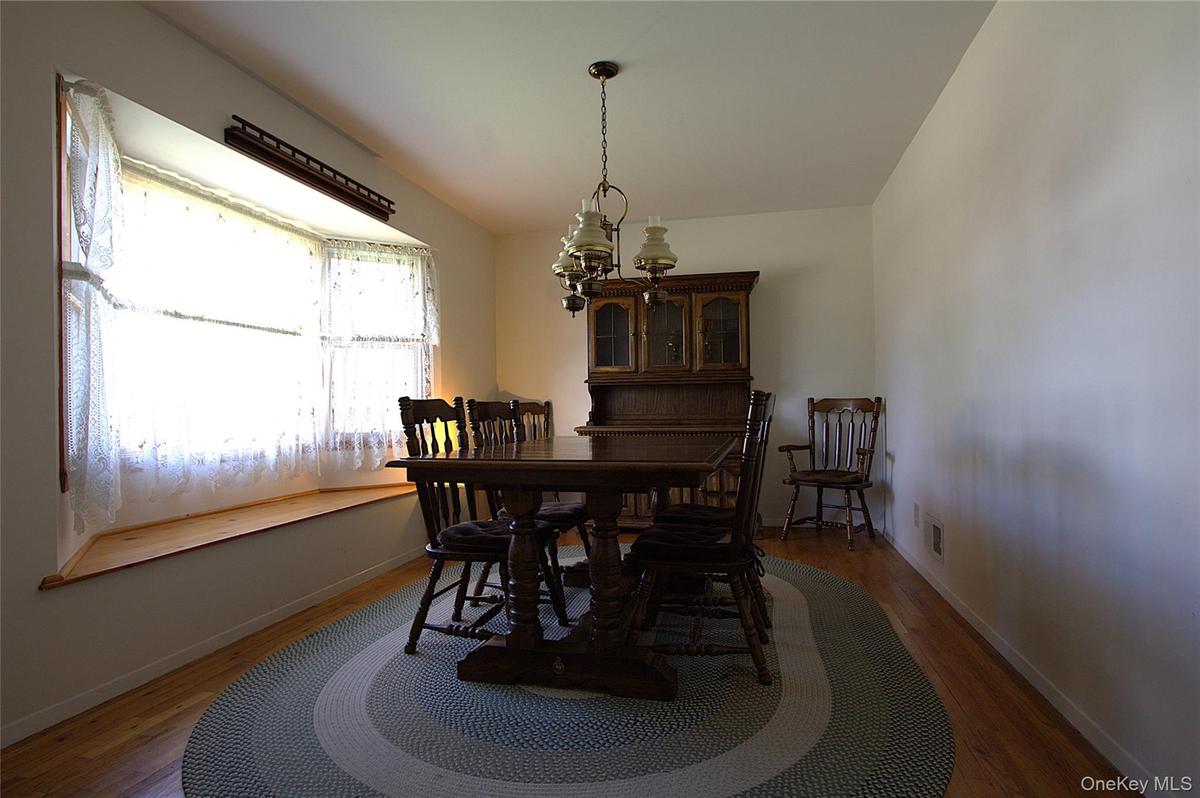 Hardwood-style flooring, a window bench with wood trim, and a classic chandelier