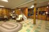 Wood paneling throughout, built-in shelving, staircase with wood railing, recessed panel ceiling, and patterned flooring
