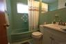 Green tiled walls with accent pattern, green bathtub, white vanity with integrated sink, and wall-mounted mirror