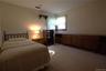 Carpeted flooring, window with natural wood trim, light-toned walls