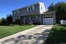 Two-story exterior with horizontal siding, attached garage with panel door, concrete driveway, and front lawn