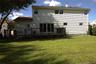 Expansive yard featuring a large wooden deck with railing, white siding, and multiple windows
