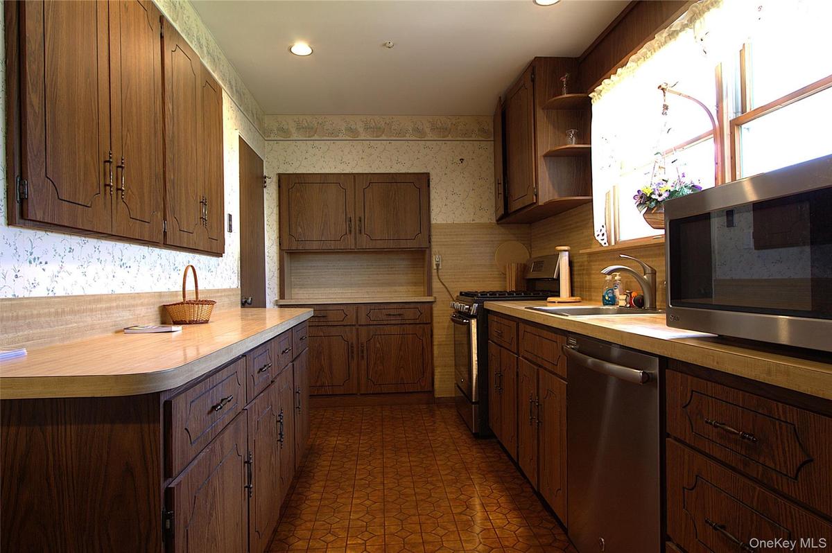 Kitchen featuring wood-finish cabinetry, light-toned countertops, and a window for natural illumination