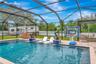 View of Outdoor Summer Kitchen; Expansive Covered Rear Lanai; Custom Pool with Sun Shelf, Fire and Waterfall feature; Pavered Floor; Additional Seatin