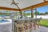 Outdoor Summer Kitchen with Stone Countertops, Bar seating, Stainless appliances, Blackstone, Grill, Sink, and More!