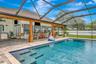 View of Outdoor Summer Kitchen; Expansive Covered Rear Lanai; Custom Pool with Sun Shelf, Fire and Waterfall feature; Pavered Floor; Additional Seatin