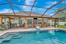 View of Outdoor Summer Kitchen; Expansive Covered Rear Lanai; Custom Pool with Sun Shelf, Fire and Waterfall feature; Pavered Floor; Additional Seatin