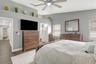 Primary Bedroom with LVP Flooring; Ceiling Fan; Decorative Ledge; En-Suite Bathroom; 2 Closets; and View to Hallway