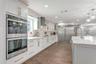 Remodeled Kitchen with upgraded custom cabinets with crown molding trim and lighting; elevated hardware and fixtures; quartz countertops; two-tone Cab