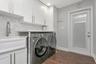 Inside Laundry Room upgraded with Front Load Washer/Dryer; LVP Flooring; White Cabinetry with upgraded hardware; Modern Utility Sink with Undermount S