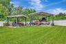 View of Backyard, Playground, Two Covered Open-Air Structured Storage areas with Concrete Pads, Firepit, and Shed. Bring the Boat- Bring the Toys - Th