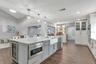 Remodeled Kitchen with upgraded custom cabinets with crown molding trim and lighting; elevated hardware and fixtures; quartz countertops; two-tone Cab