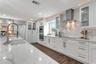 Remodeled Kitchen with upgraded custom cabinets with crown molding trim and lighting; elevated hardware and fixtures; quartz countertops; two-tone Cab
