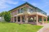 Waterfront-side exterior highlighting the expansive covered outdoor entertaining space.